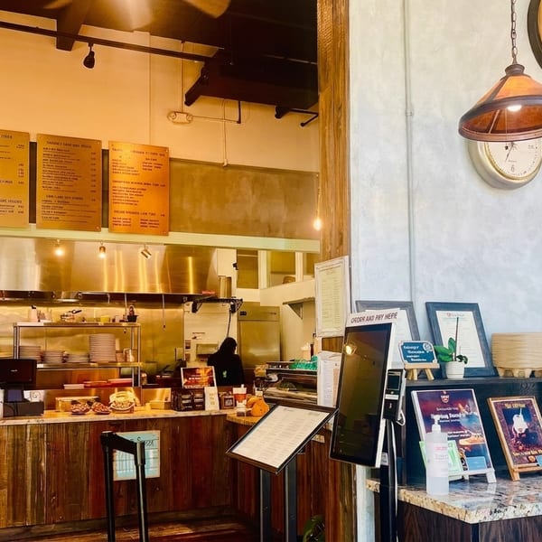 A rustic-industrial restaurant interior with a counter, menu boards, and decorative clocks on the wall.