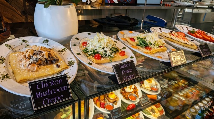 Savory crepes, including Chicken Mushroom and Turkey Pesto, displayed in a restaurant's glass case.